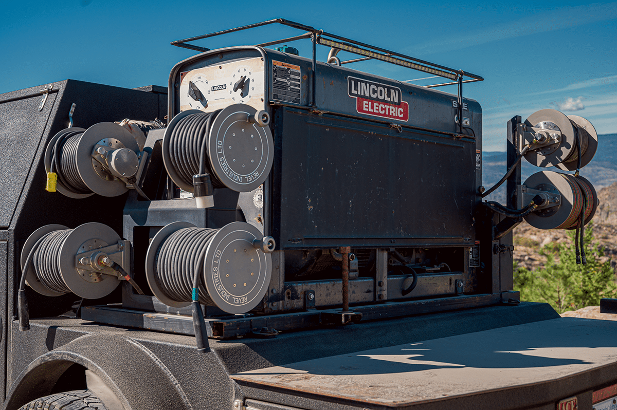 A large truck towing a trailer, equipped with four loaded reels, parked on a road