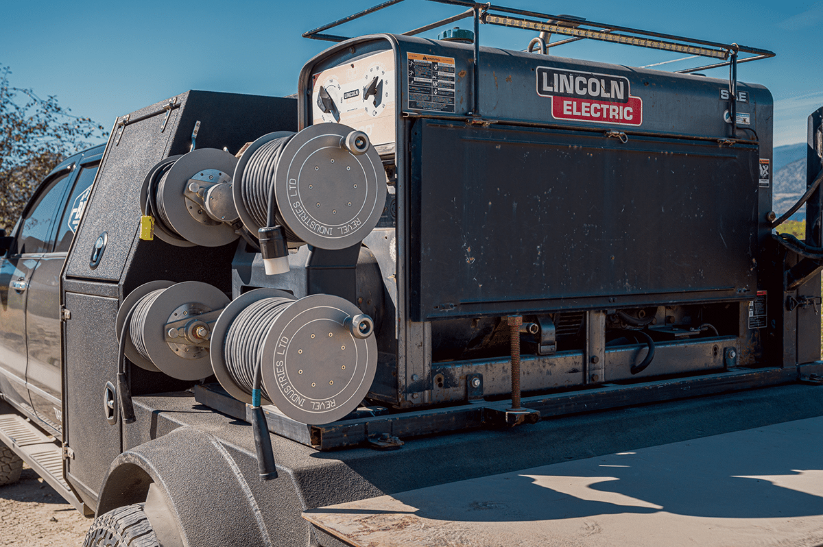 A truck equipped with a powerful engine is driving along a dirt road, carrying reels for different uses