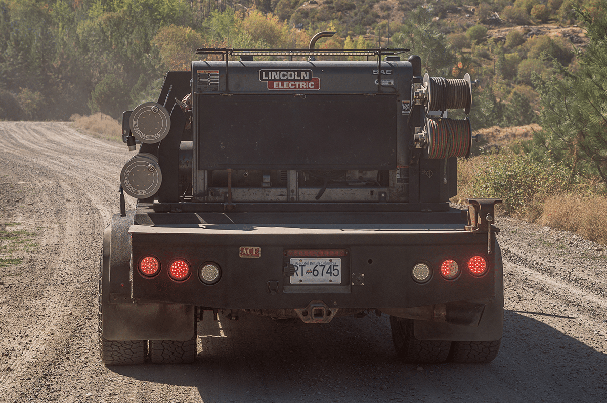 A truck driving on a dirt road, transporting large reels with its powerful engine