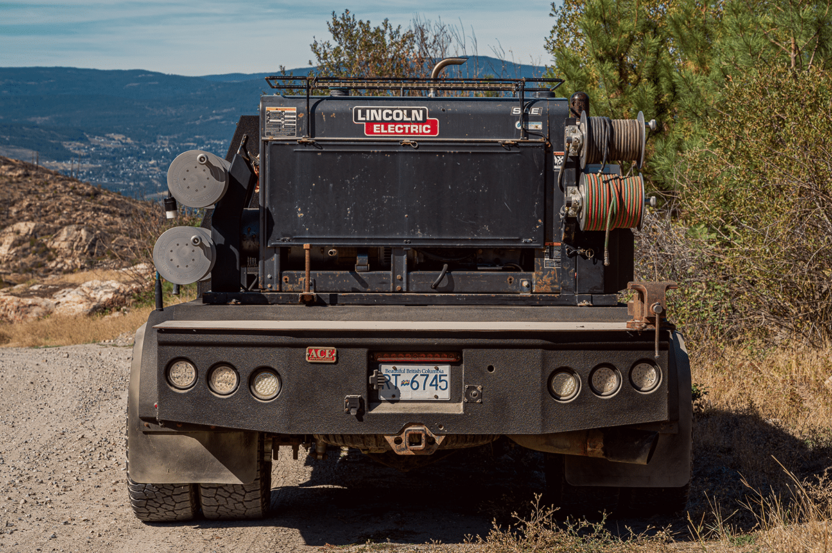 A truck drives along a dirt road, transporting reels in its cargo bed