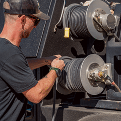 A man is setting up reels while working on a truck with a hose